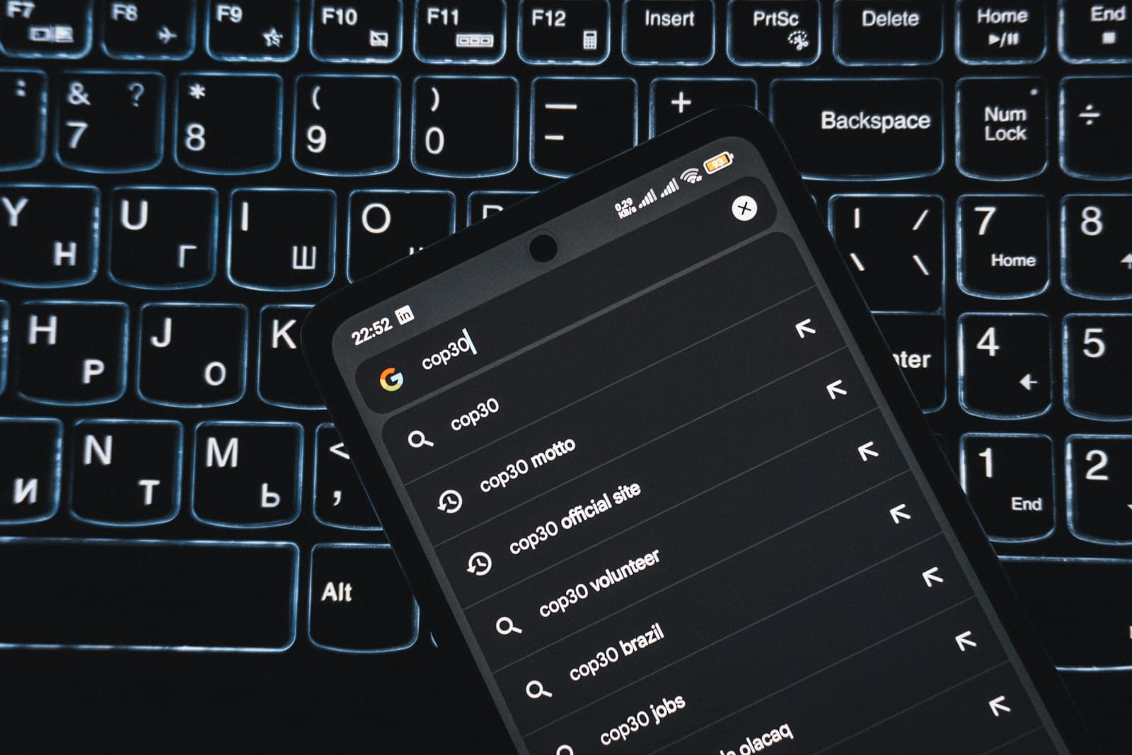 Smartphone met zoekresultaten op een verlicht toetsenbord